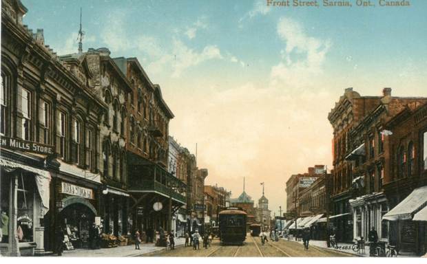 A busy street with a streetcar and shop awnings.