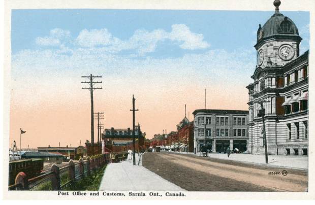 A wide street beside a large stone building with a clock tower.