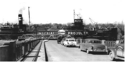 A tanker lettered Imperial Products alongside a dock, with 1950s cars parked in the foreground.