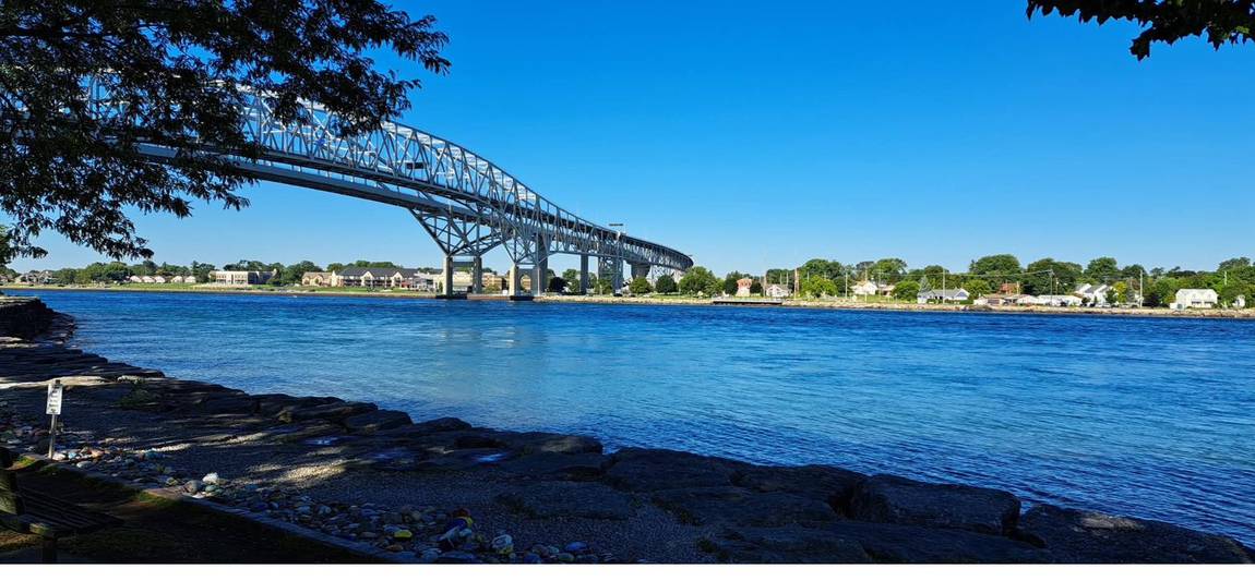 The Blue Water Bridge in bright daylight seen from a rocky shoreline.