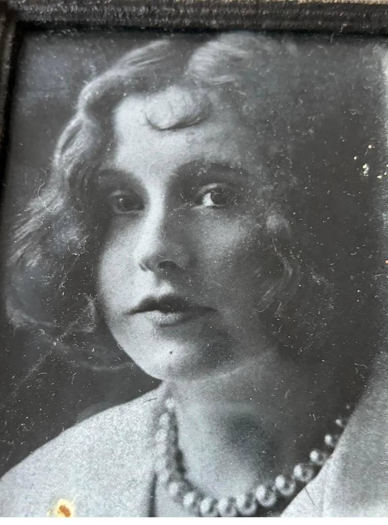 A soft-focus studio portrait of a young woman with wavy hair and a pearl necklace.