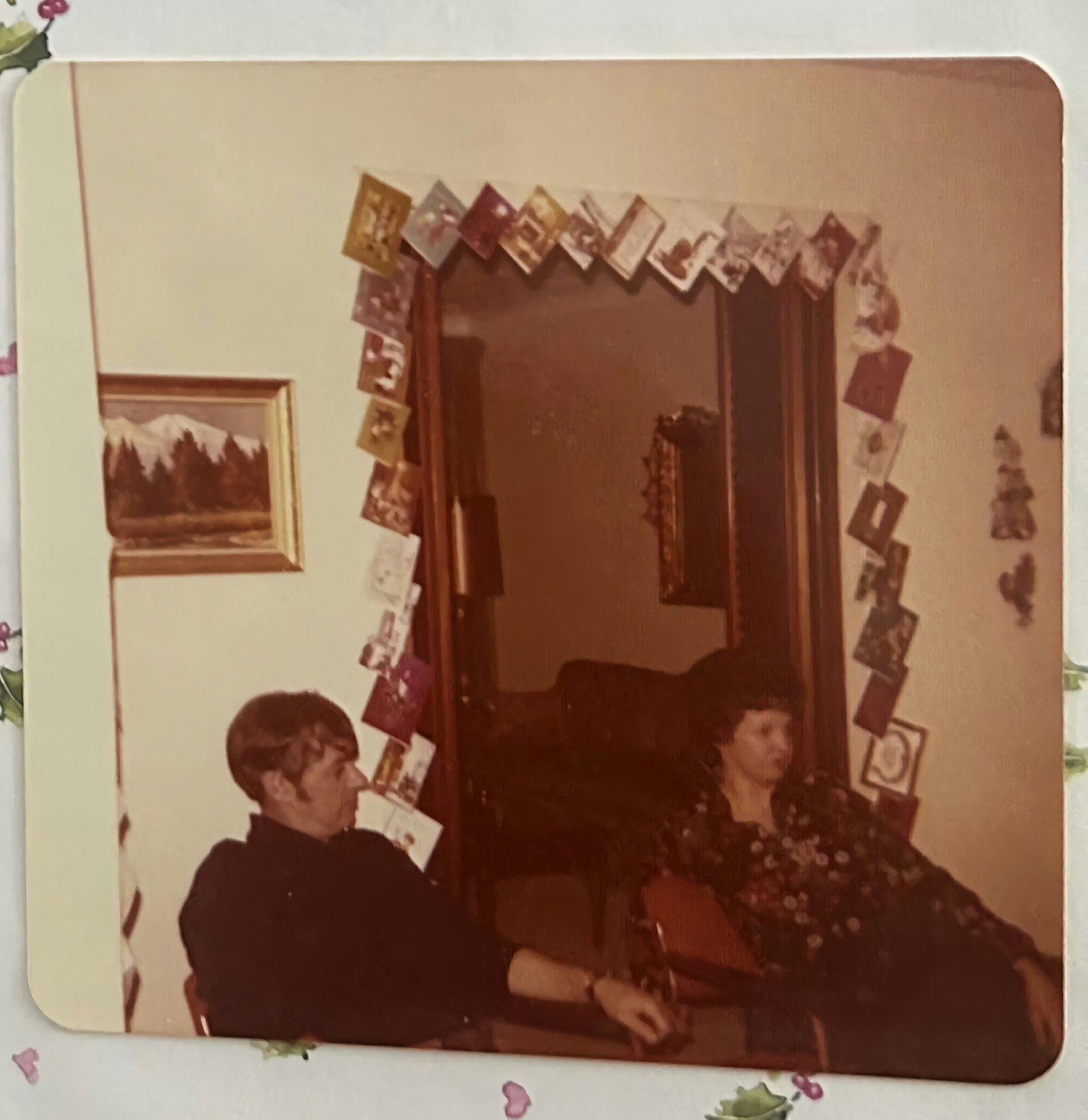 Robert and Donna Davies seated together at Christmas beneath a doorway lined with Christmas cards