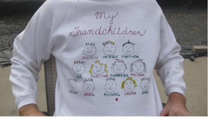 A white sweatshirt embroidered 'My Grandchildren' with twelve names and twelve small faces.