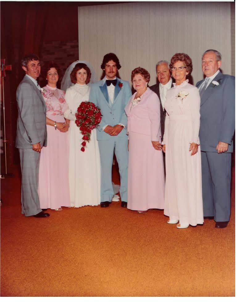A 1970s wedding group: bride and groom flanked by two older couples in formal dress.